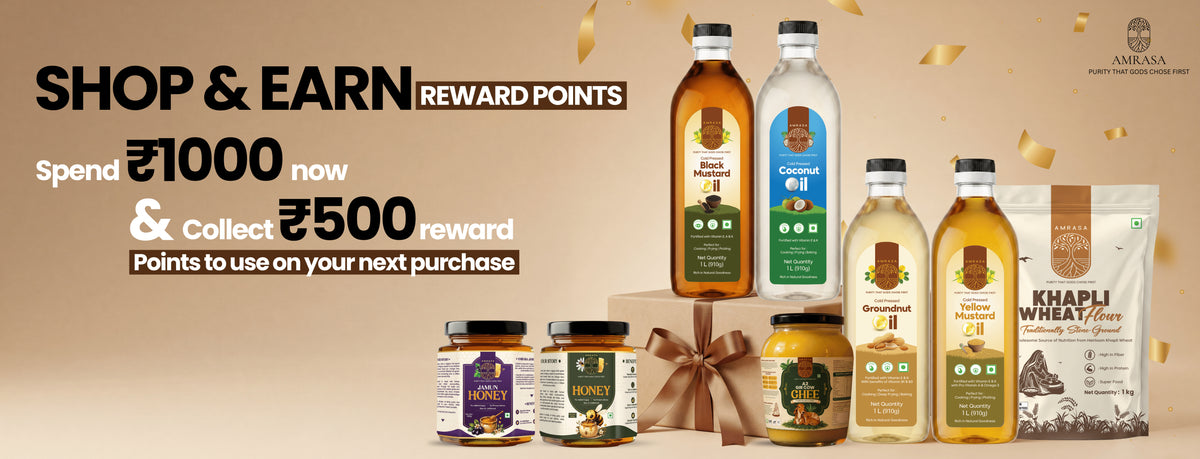 A promotional banner for Aaravi's Rewards program featuring various bottles and jars of cooking oils, spreads, and wheat flour. The products are arranged on a warm beige background with gold confetti and a central gift box.